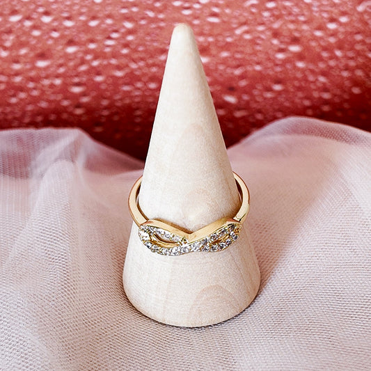 Gold ring on a white cone-shaped stand with a textured red background