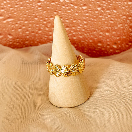 Gold ring on a white cone against a textured pinkish-beige background