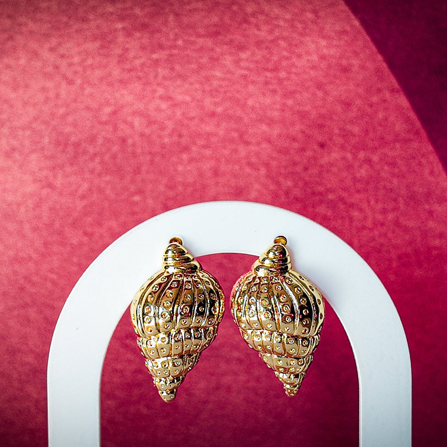 Gold earrings on a pink background